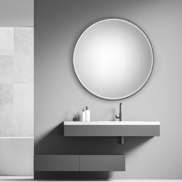 Bathroom silver round mirror above vanity.